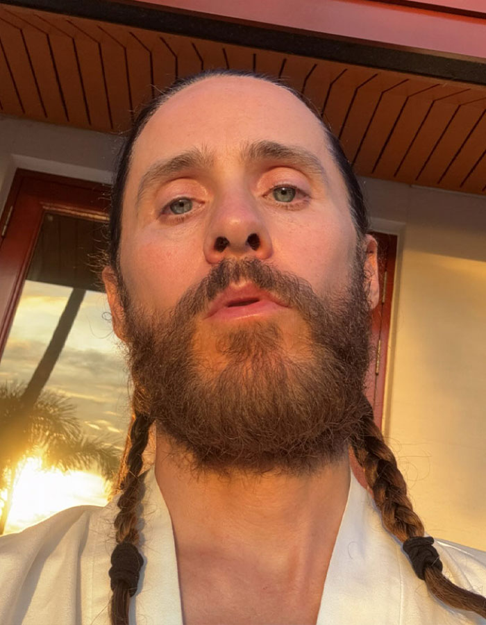Close-up of Jared Leto with braided hair and beard, facing camera outdoors with golden hour sunlight. Close-up of Jared Leto with braided hair and beard, facing camera outdoors with golden hour sunlight.