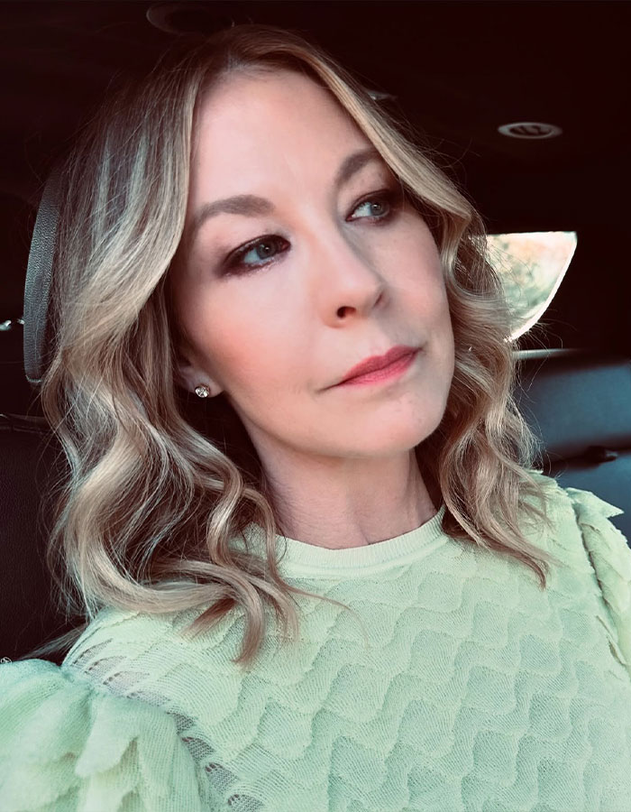 Famous 90s actress aged 53 with youthful look, wavy blonde hair, wearing light green textured top in a car. Famous 90s actress aged 53 with youthful look, wavy blonde hair, wearing light green textured top in a car.