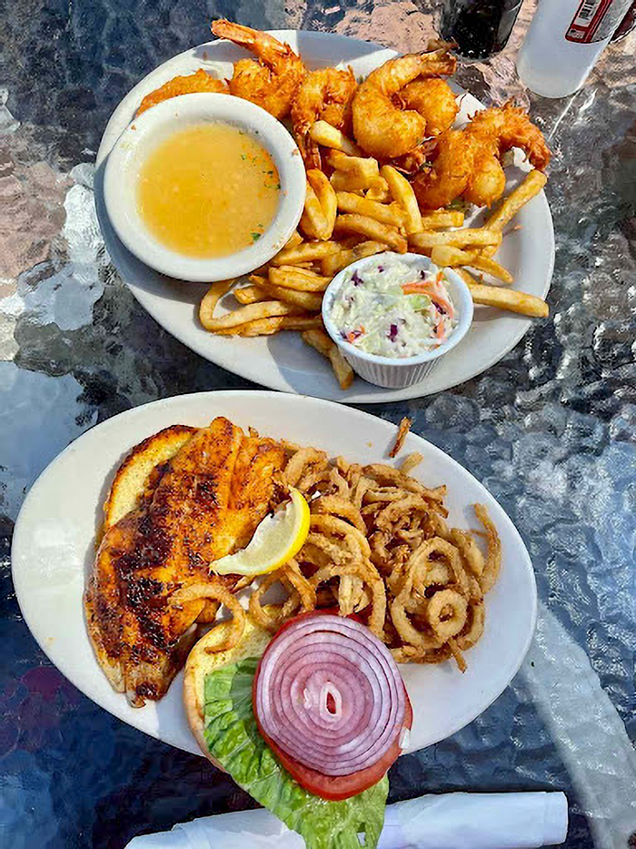 Plate of fried shrimp, fish sandwich with onion and lettuce, fries, and coleslaw showcasing Siesta Key foodie's hidden gems. Plate of fried shrimp, fish sandwich with onion and lettuce, fries, and coleslaw showcasing Siesta Key foodie's hidden gems.