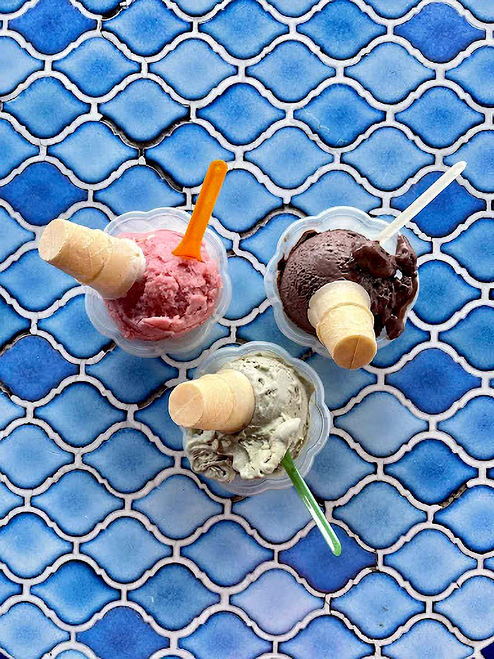 Three scoops of colorful ice cream with mini cones in clear cups on a blue tiled surface in Siesta Key. Three scoops of colorful ice cream with mini cones in clear cups on a blue tiled surface in Siesta Key.