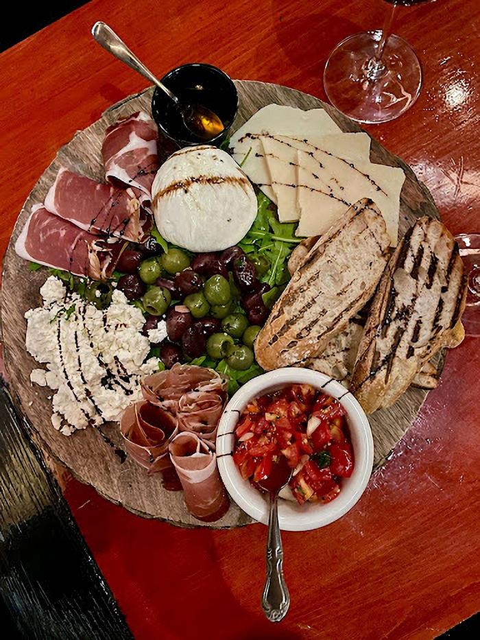 Charcuterie board with prosciutto, cheese, olives, grilled bread, and tomatoes, showcasing foodie’s guide to Siesta Key. Charcuterie board with prosciutto, cheese, olives, grilled bread, and tomatoes, showcasing foodie’s guide to Siesta Key.