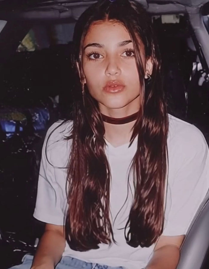 Young woman with long brown hair and choker sitting in a car, linked to Kim Kardashian throwback and plastic surgeries discussion. Young woman with long brown hair and choker sitting in a car, linked to Kim Kardashian throwback and plastic surgeries discussion.