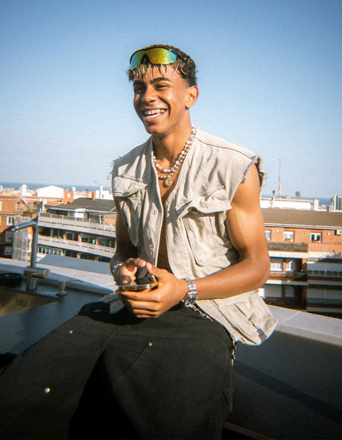 Young man smiling outdoors in sleeveless vest and sunglasses, related to fans finding old comment on thirst trap. Young man smiling outdoors in sleeveless vest and sunglasses, related to fans finding old comment on thirst trap.