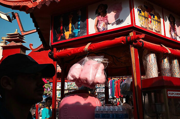 Street vendor selling cotton candy and popcorn in a busy market, captured by a photographer traveling the world.