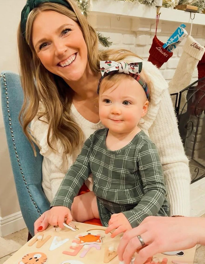 Smiling woman and toddler playing with a puzzle by the fireplace, illustrating real housewives exec and her two children. Smiling woman and toddler playing with a puzzle by the fireplace, illustrating real housewives exec and her two children.