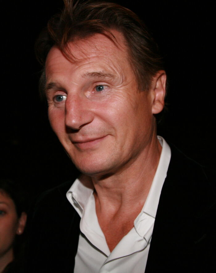 Middle-aged man with light blue eyes and brown hair wearing a white shirt and black jacket in a dimly lit setting representing late bloomers.