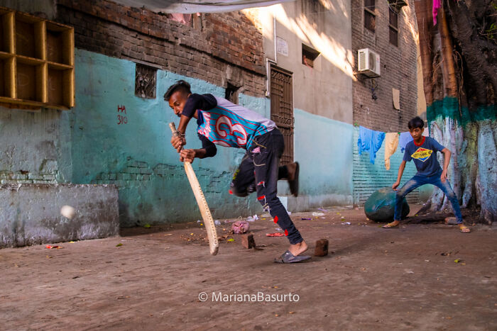 Young boys playing street cricket in an urban alley, capturing the unseen realities of our world through photography.