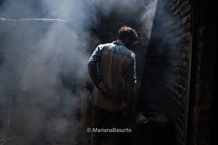 Person standing in a dimly lit smoky room, capturing the unseen realities of our world through photography.