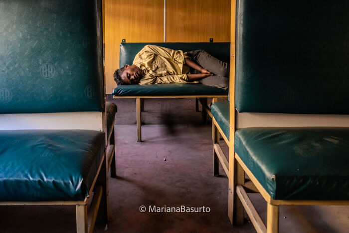 Young man sleeping on a bench inside an empty train, capturing unseen realities of our world by the photographer.