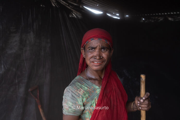 Portrait of a woman revealing unseen realities of our world, wearing traditional clothing in a dimly lit setting.