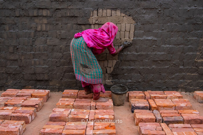 Woman in colorful clothes laying bricks while revealing unseen realities of hard labor in the world through photography.