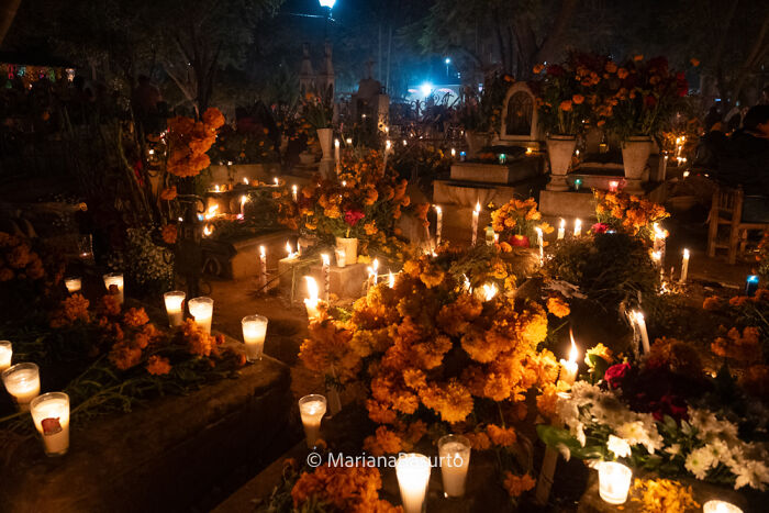 Colorful cemetery illuminated by candles and marigold flowers, revealing unseen realities captured by photographer's lens.