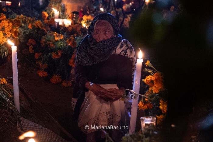 Elderly woman surrounded by candles and marigolds, capturing unseen realities in a powerful photographer's shot.