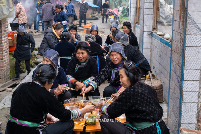 Group of people in traditional clothing sharing a meal outdoors, showcasing unseen realities captured by a photographer.