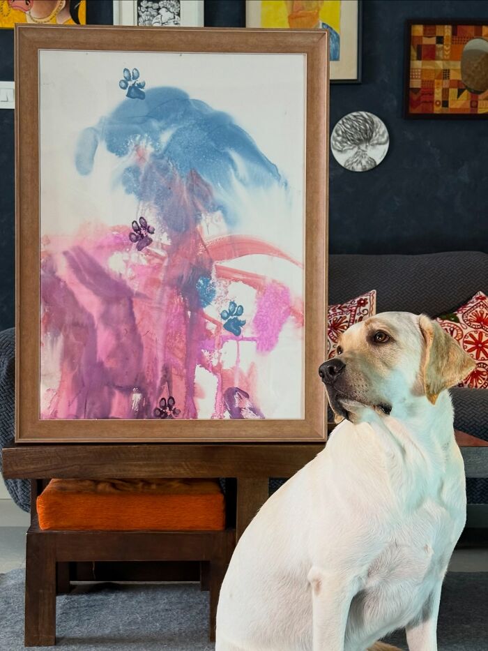 Rescue Labrador sitting beside colorful abstract painting with paw prints, showcasing unique art created by the dog. Rescue Labrador sitting beside colorful abstract painting with paw prints, showcasing unique art created by the dog.