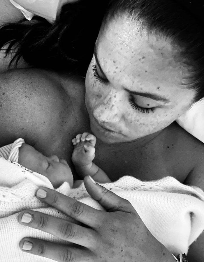 Meghan Markle holding newborn baby close, showcasing intimate mother and child moment in black and white photo. Meghan Markle holding newborn baby close, showcasing intimate mother and child moment in black and white photo.
