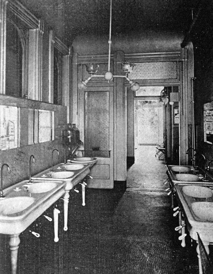 Black and white historical image of a washroom with vintage sinks and fixtures, showcasing historical facts and design.