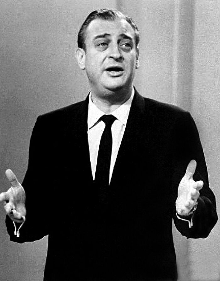 Black and white photo of a late bloomer millionaire speaking passionately in a suit and tie on stage.