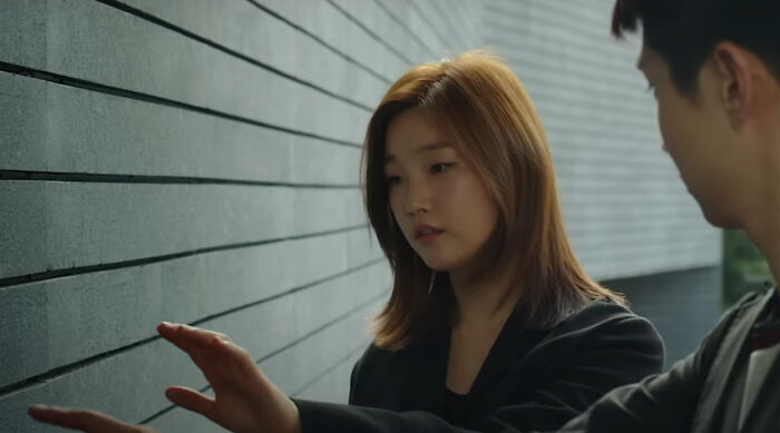 Young woman touching textured wall while discussing scene with man, representing new millennium's greatest films you need to see.