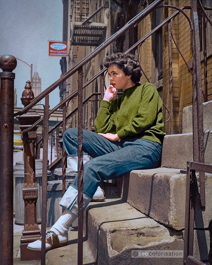 Colorized historical photo of a woman sitting thoughtfully on urban stone steps with vintage iron railings.