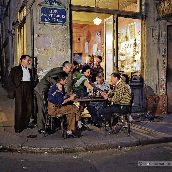 Colorized historical photo of people socializing outside a Paris cafe at night, showcasing magical historical moments recreated.