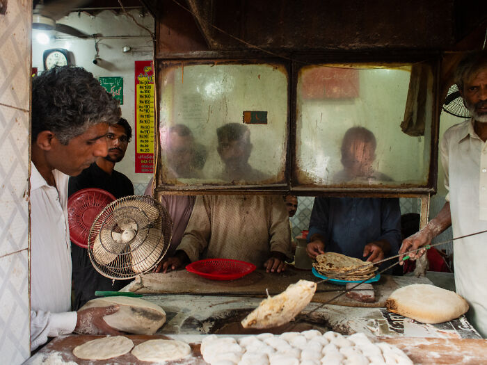 Street moment showing a baker preparing flatbread in a traditional bakery, capturing candid emotion and daily life.