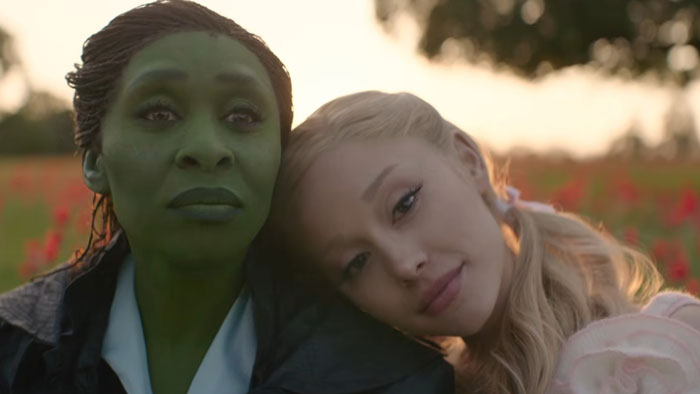 Two main characters from the new Wicked movie, one with green makeup and another as Dorothy, in an outdoor scene. Two main characters from the new Wicked movie, one with green makeup and another as Dorothy, in an outdoor scene.