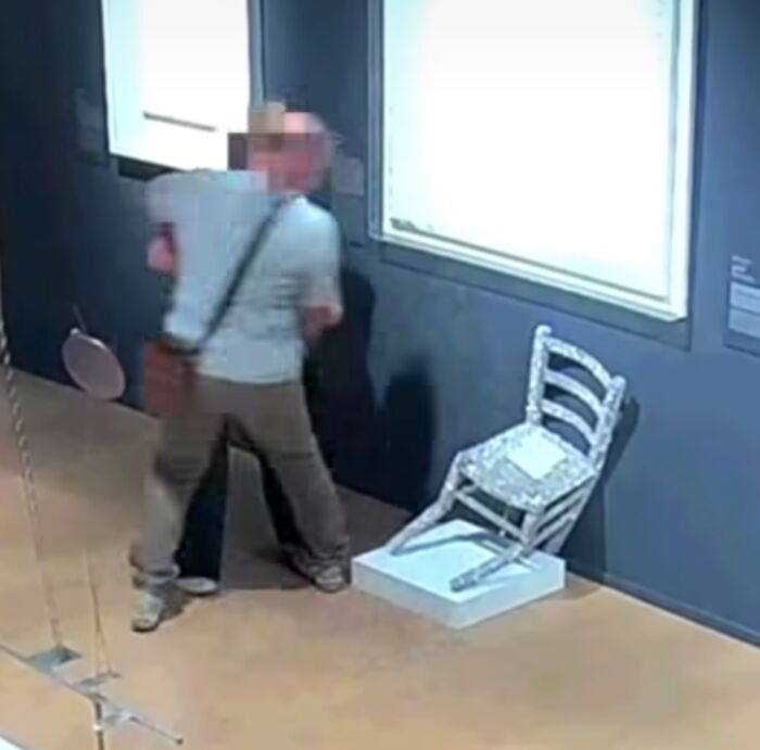 Tourist in a museum near an 18th century painting, caught on camera before accidentally ripping the artwork while taking a selfie.