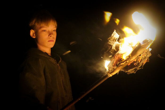 Young boy holding a burning torch in the dark, symbolizing people revealing totally acceptable baby names that weird them out.