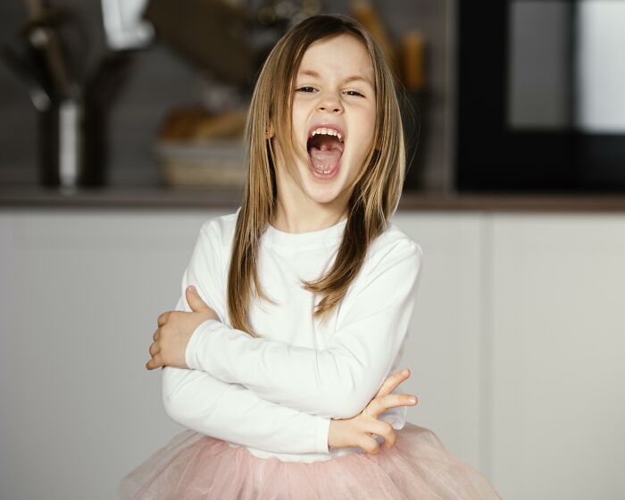 Young girl in a white shirt and pink tutu expressing surprise, representing unusual baby names that secretly weird them out.