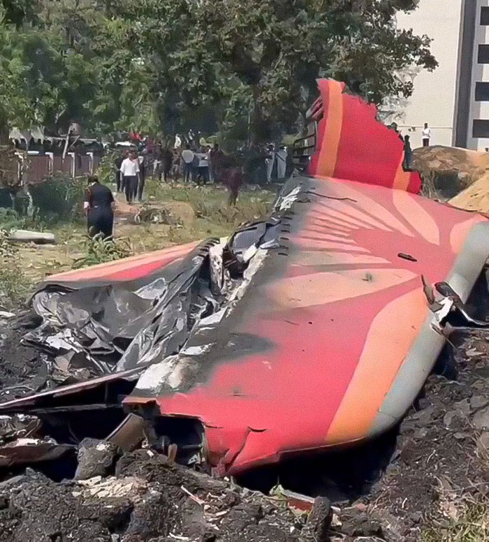 Wreckage of an Air India Boeing jet with visible damage, surrounded by people and trees in the background after crash. Wreckage of an Air India Boeing jet with visible damage, surrounded by people and trees in the background after crash.