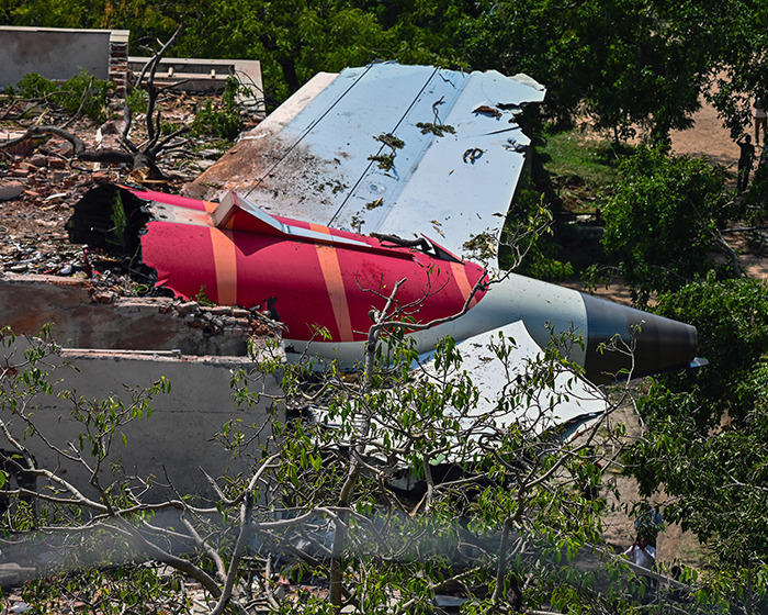 Air India plane wreckage showing damaged tail section surrounded by trees in eerie silence before crash investigation. Air India plane wreckage showing damaged tail section surrounded by trees in eerie silence before crash investigation.