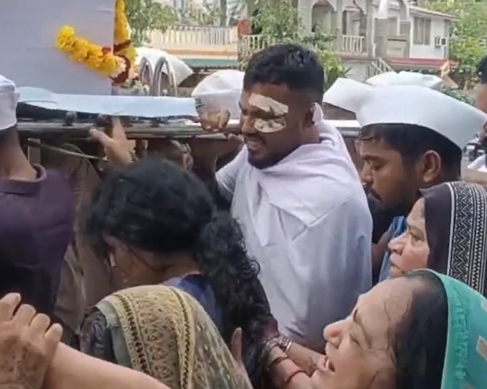 Man with eye bandage, wearing white, carrying coffin during Air India crash survivor's emotional funeral procession. Man with eye bandage, wearing white, carrying coffin during Air India crash survivor's emotional funeral procession.