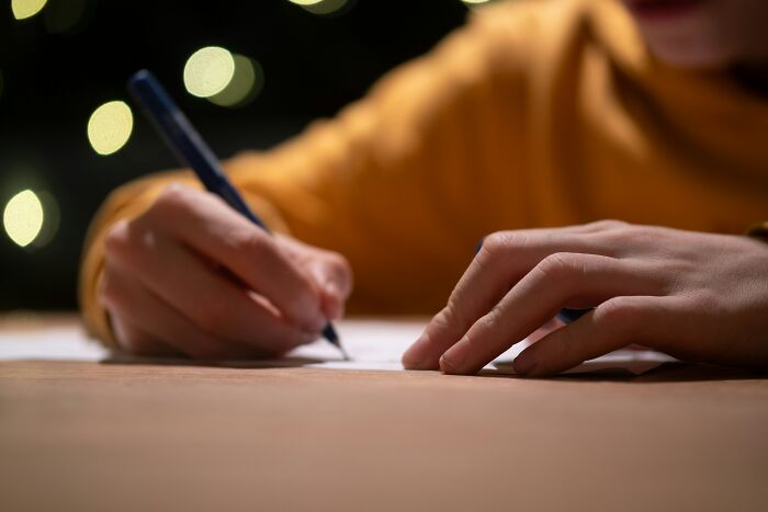 Person in a warm shirt writing with a pen on paper, illustrating people share most privileged things said concept.