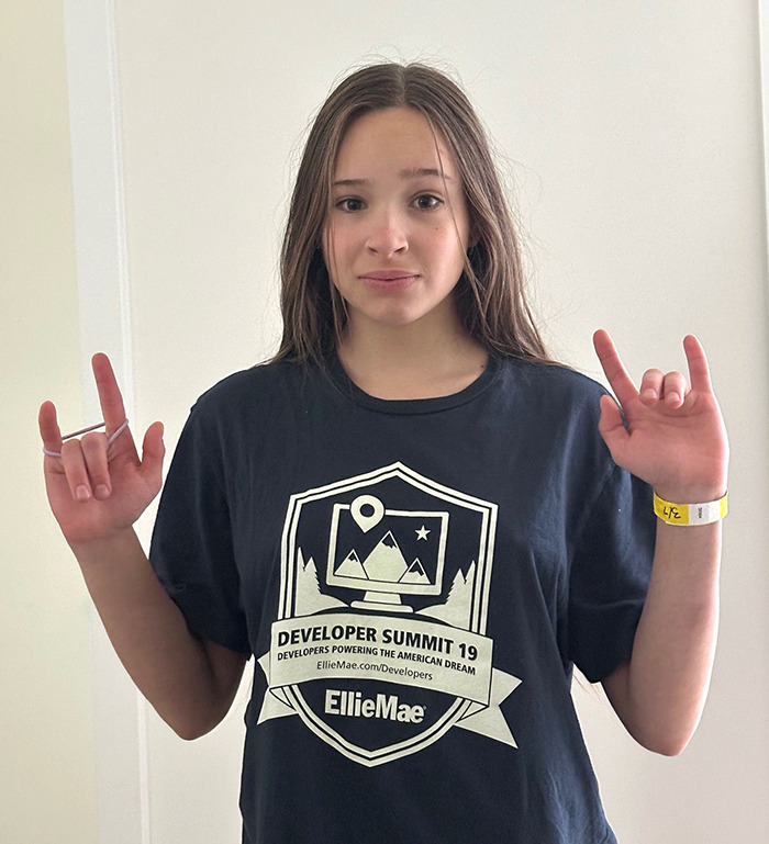Teenage girl found alive after six weeks missing, wearing a black graphic tee and making hand signs indoors. Teenage girl found alive after six weeks missing, wearing a black graphic tee and making hand signs indoors.
