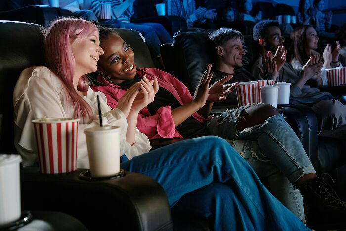 Two women enjoying a movie in a theater, smiling and clapping while a good trend slowly disappeared in the background.