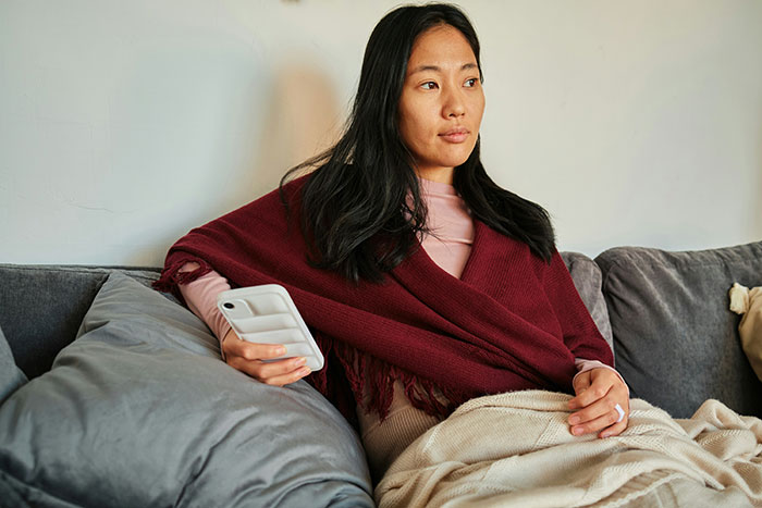 Woman wrapped in a blanket sitting on a couch, reflecting on psoriasis and body makeup issues before a wedding event. Woman wrapped in a blanket sitting on a couch, reflecting on psoriasis and body makeup issues before a wedding event.