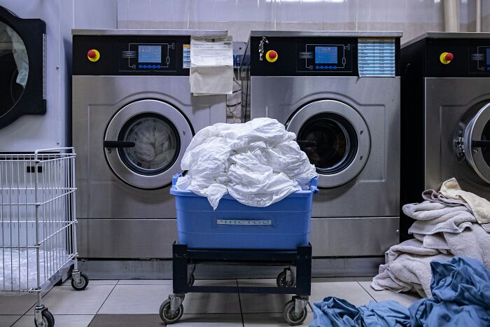 Laundry in progress at an industrial laundromat with people sharing most privileged things said in the background.