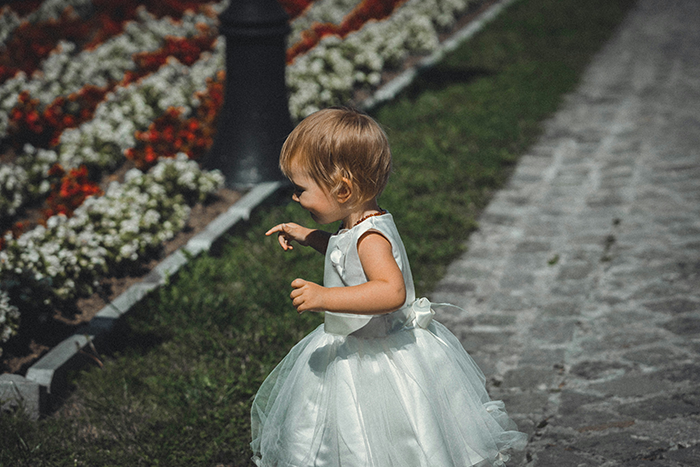 Young child wearing a white dress at an outdoor family wedding, capturing moments related to bride’s legacy.