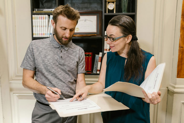 Man and woman reviewing documents in office setting, illustrating a husband filing for divorce amid baby gender dispute. Man and woman reviewing documents in office setting, illustrating a husband filing for divorce amid baby gender dispute.