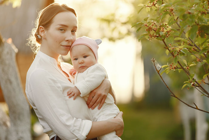 Young mother holding baby outdoors at sunset, reflecting MIL convinced pregnant DIL manipulated baby’s gender issue. Young mother holding baby outdoors at sunset, reflecting MIL convinced pregnant DIL manipulated baby’s gender issue.