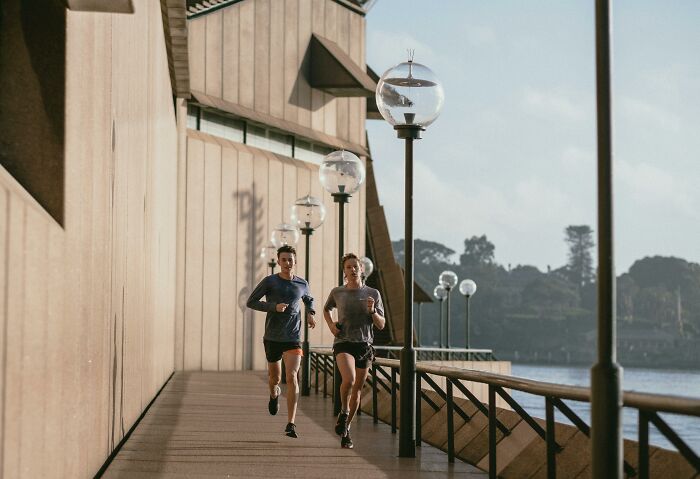 Two people running along a waterfront path with lamps, highlighting bad things people face in everyday life.