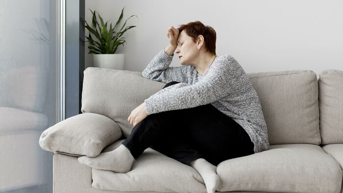 Woman sitting on a couch looking stressed and tired, illustrating bad things people experience in life.