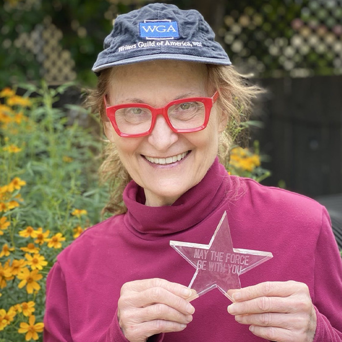 Beloved ’90s star and Rain Man co-star smiling outdoors, wearing a WGA hat and holding a star-shaped award. Beloved ’90s star and Rain Man co-star smiling outdoors, wearing a WGA hat and holding a star-shaped award.