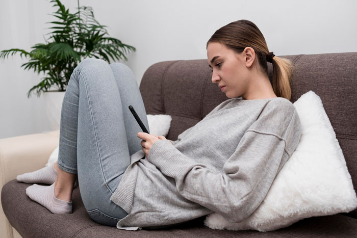 Young woman in casual clothes sitting on a couch looking troubled, highlighting friendship of 10 years on the rocks.
