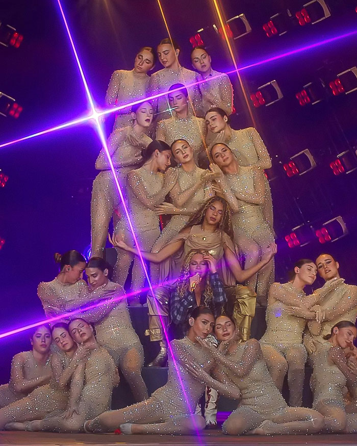 Beyoncé performing with dancers in sparkling outfits under purple stage lights during controversial cigarette stunt on tour. Beyoncé performing with dancers in sparkling outfits under purple stage lights during controversial cigarette stunt on tour.
