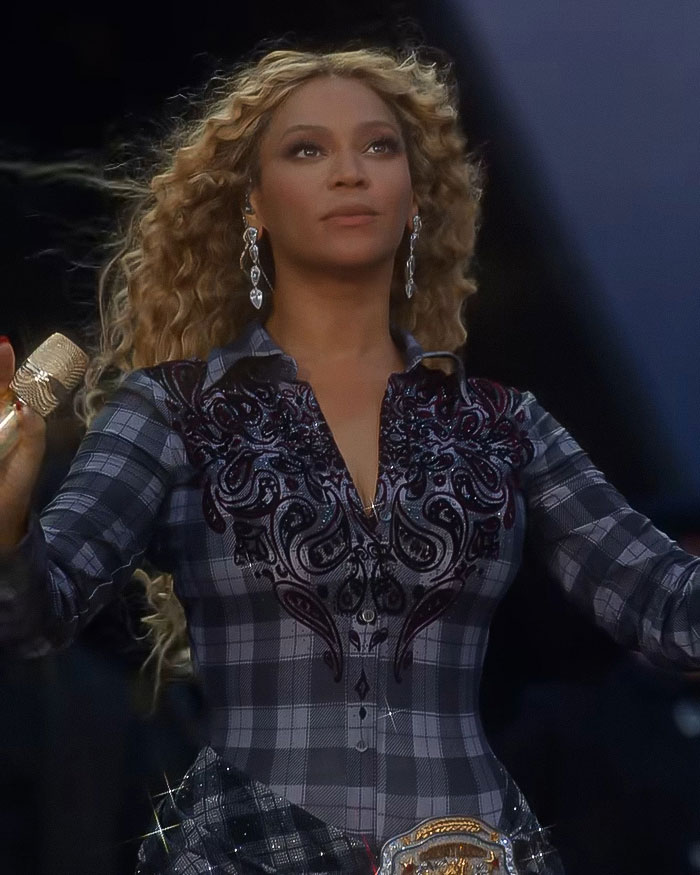 Beyoncé performing on stage with curly hair and paisley dress during a show sparking cigarette stunt controversy.