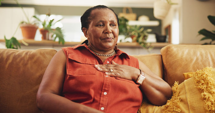 African American teacher sitting on a couch, reflecting on paying family’s bills and being called selfish and whitewashed. African American teacher sitting on a couch, reflecting on paying family’s bills and being called selfish and whitewashed.