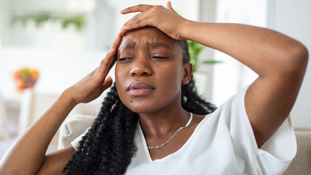 Woman with long braided hair showing stress and frustration while sitting indoors reflecting on family bills and selfishness