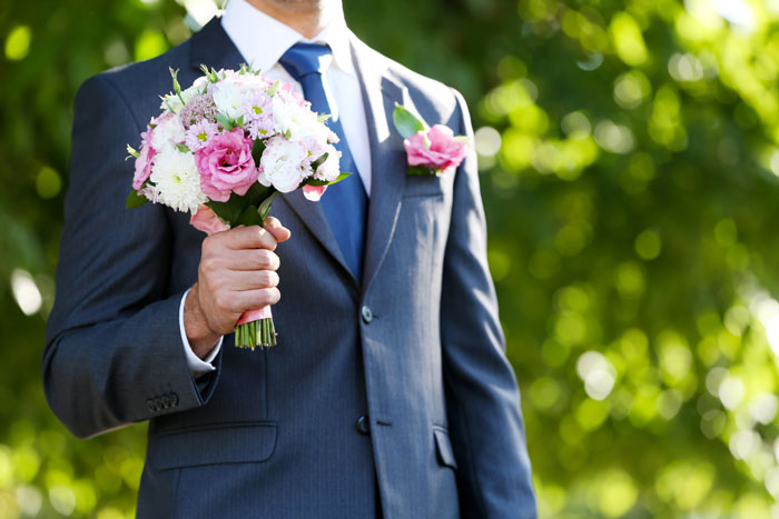 Man in a suit holding a wedding bouquet outdoors, ready to present to the bride on their special day. Man in a suit holding a wedding bouquet outdoors, ready to present to the bride on their special day.